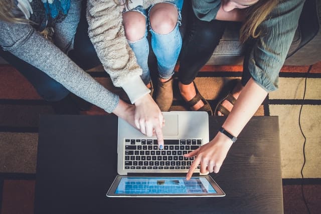 Three women looking at a laptop screen. 