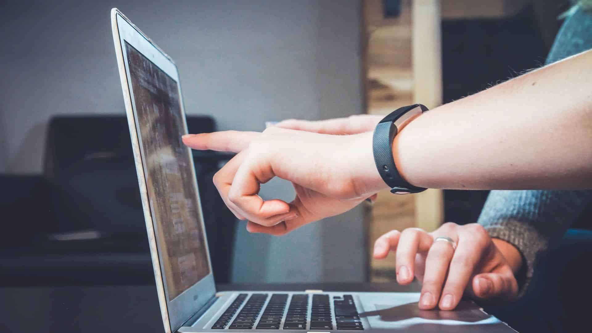 A client pointing something out to a web designer on a laptop screen