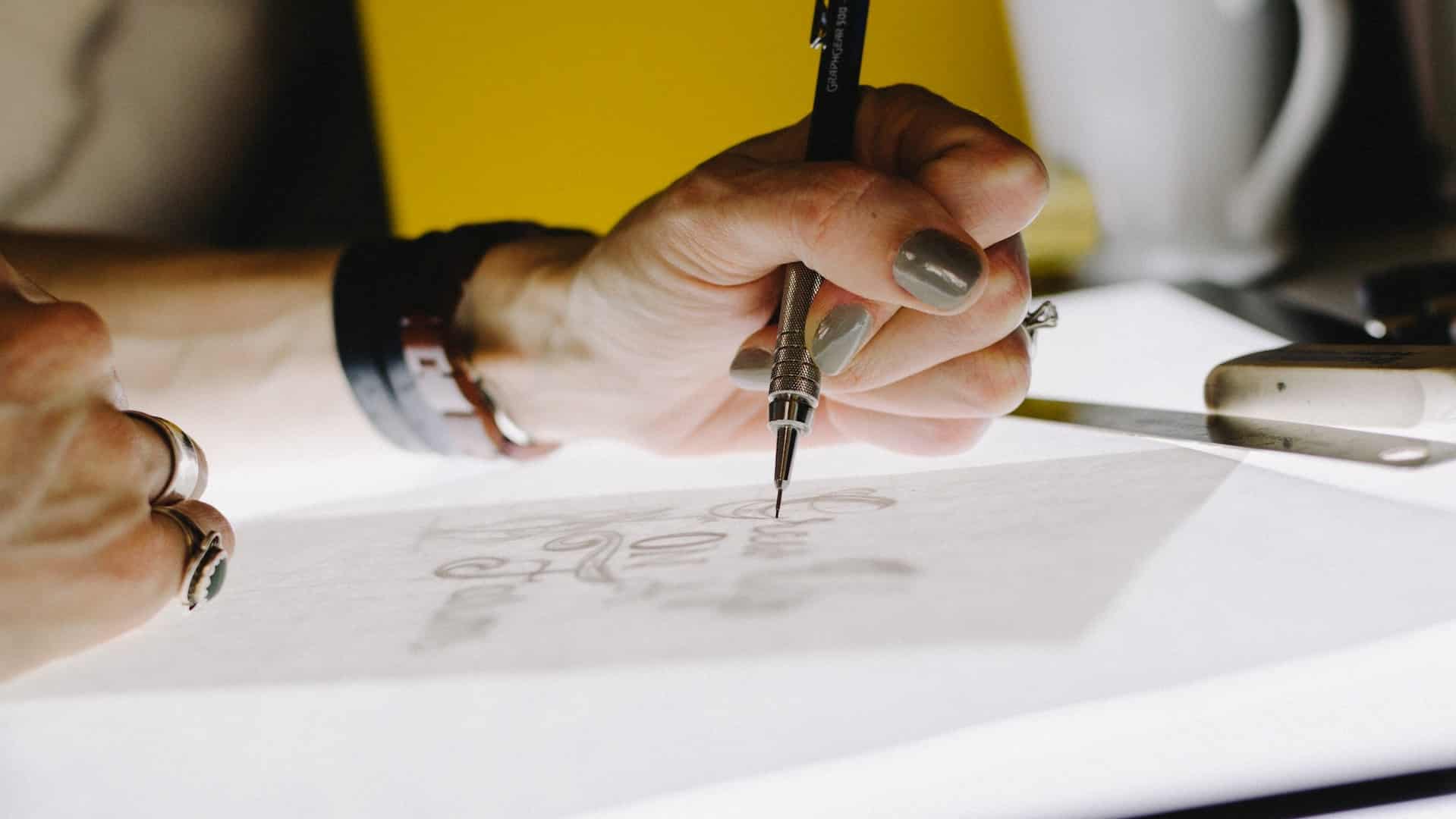 A person designing a company logo on a piece of paper.