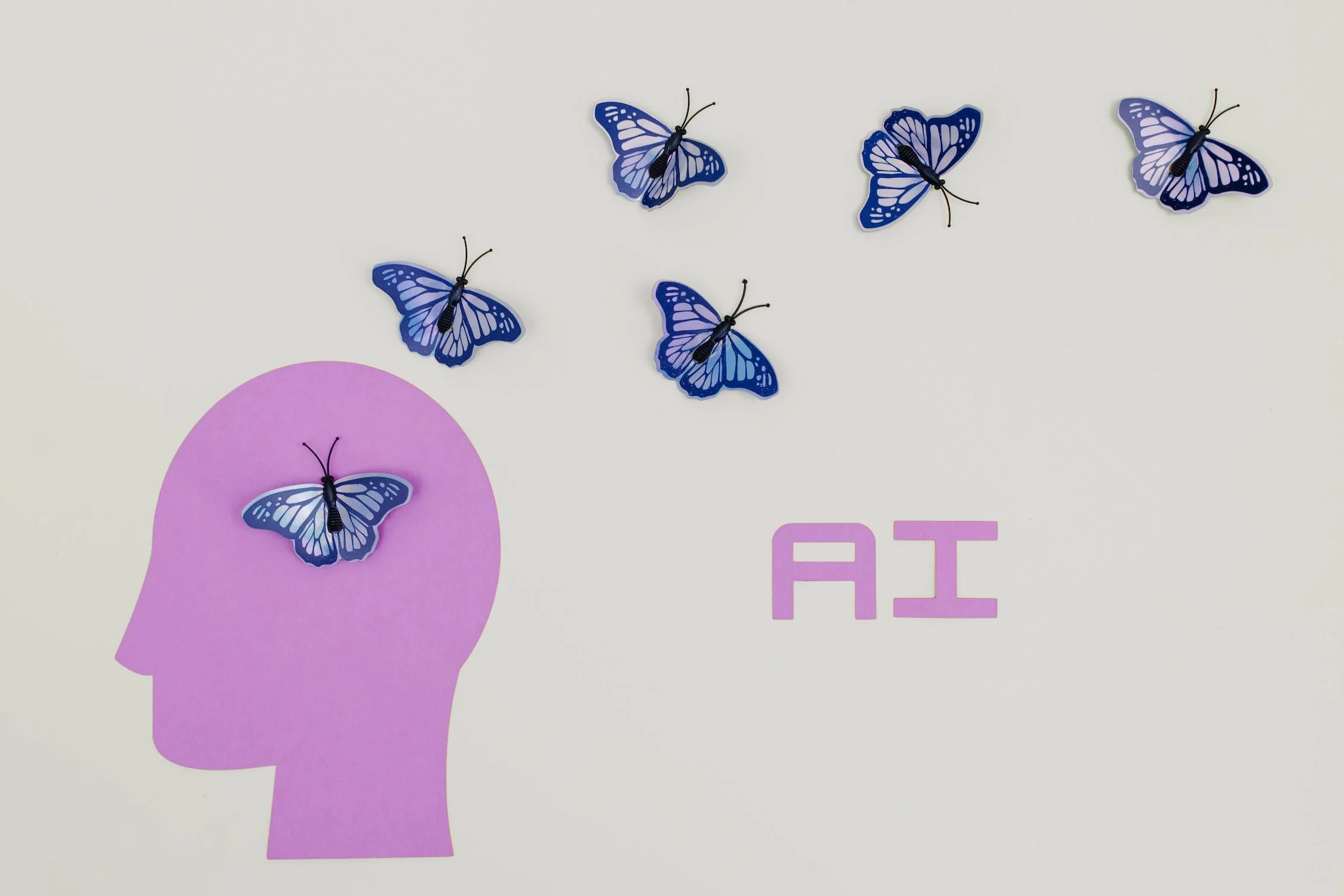 An illustration of butterflies and a pink head silhouette that reads “AI.”