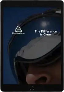 A close-up of a person wearing ski goggles reflects a snowy mountain scene. Text reads MotoSolutions with a logo and The Difference is Clear. The image is displayed on a tablet screen.