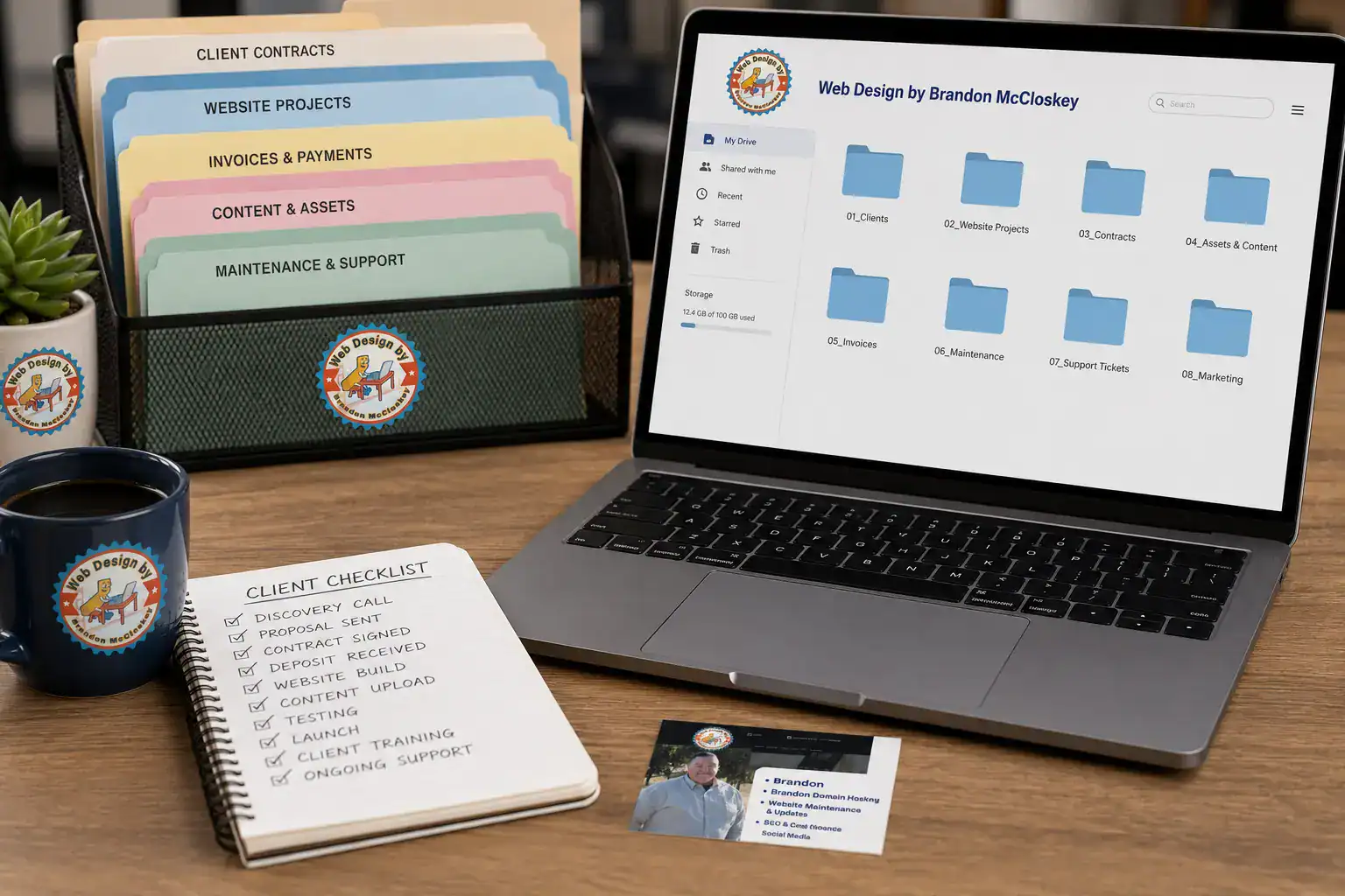 Desk with laptop showing folders, a file organizer with labeled folders, a mug, a small plant, business cards, and a notepad with a handwritten client checklist. Office workspace setting for a web design business.